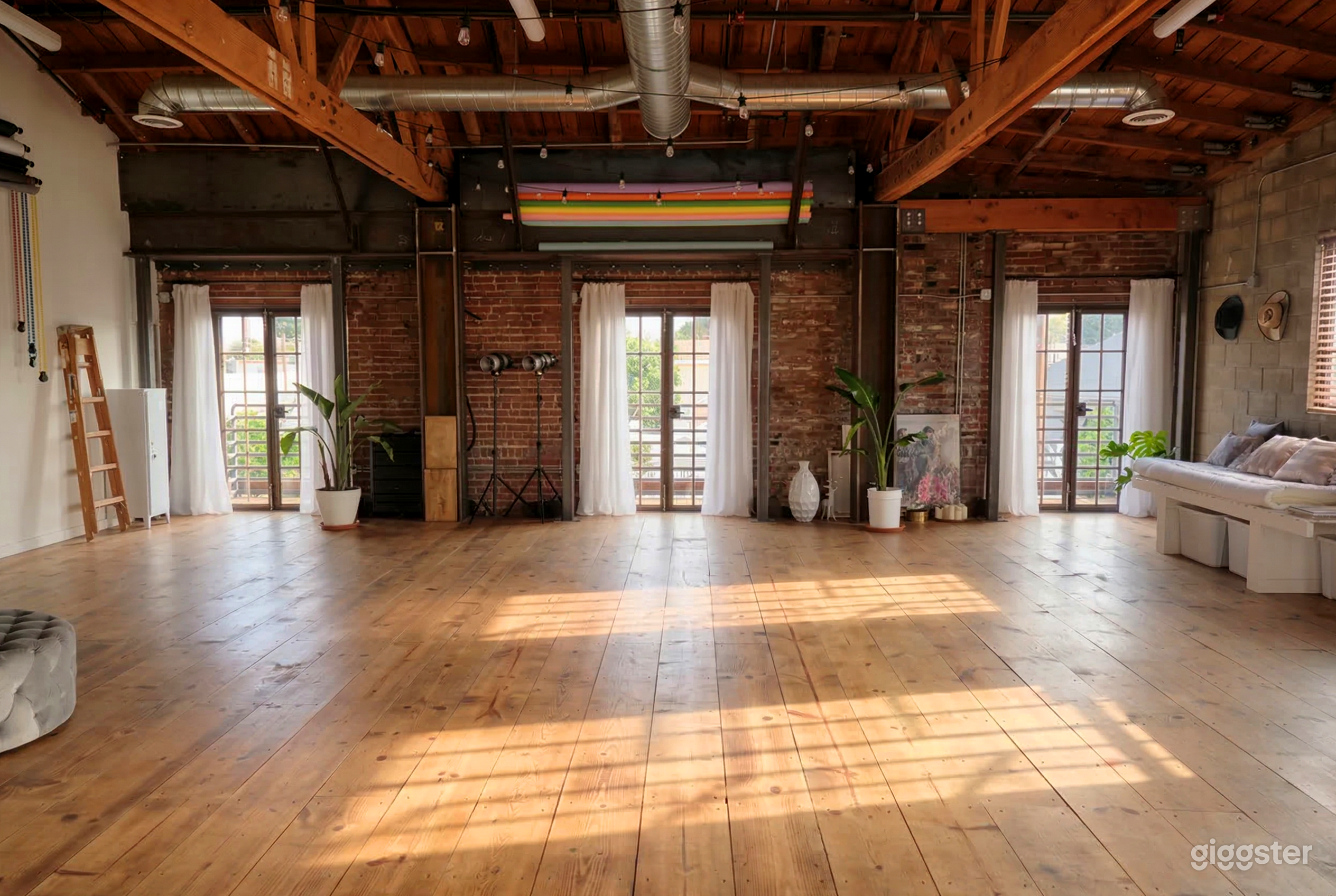 An industrial style room with pipe bare ceiling and an open space with a couch on one side and decor items against the front brick wall.