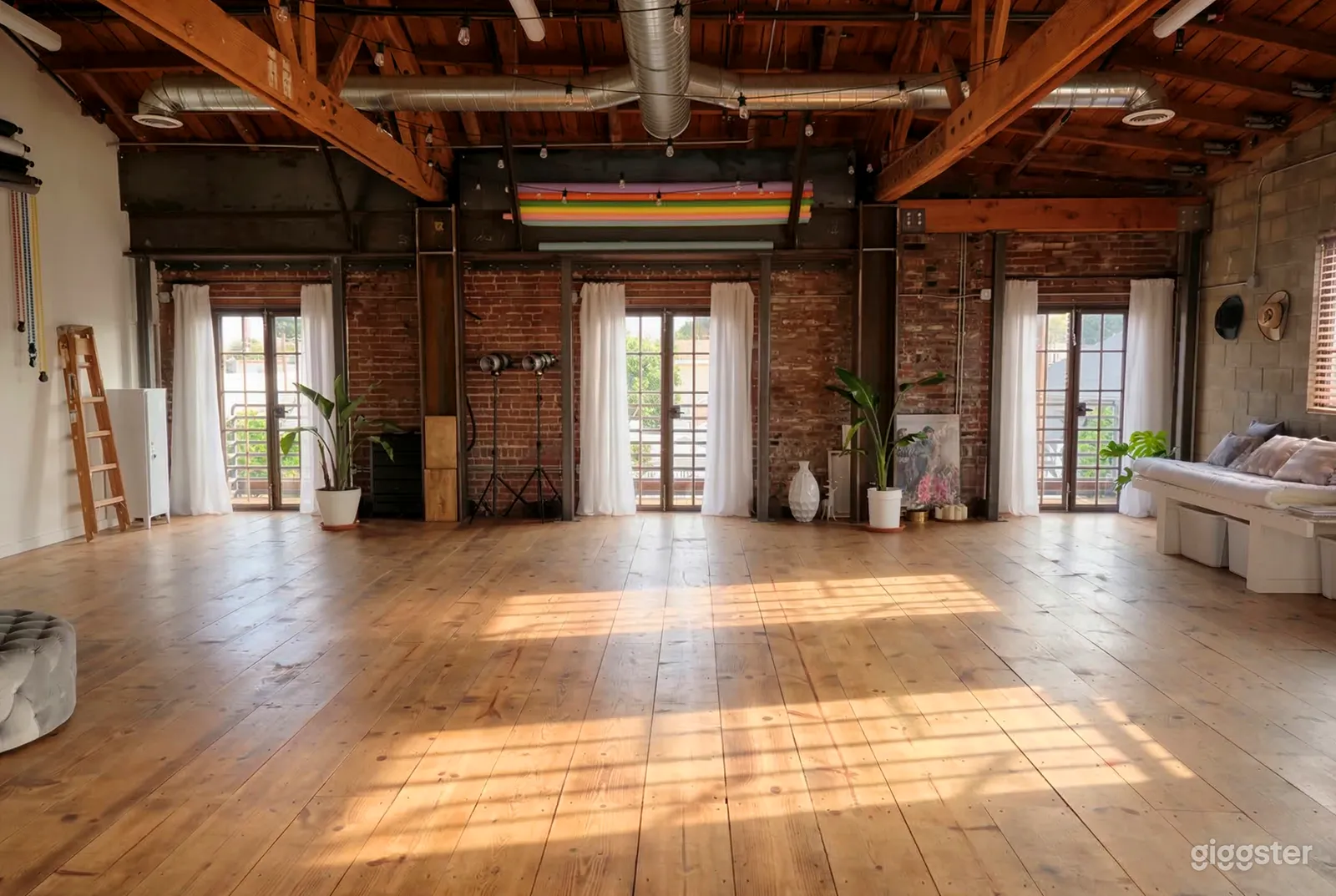 An industrial style room with pipe bare ceiling and an open space with a couch on one side and decor items against the front brick wall.