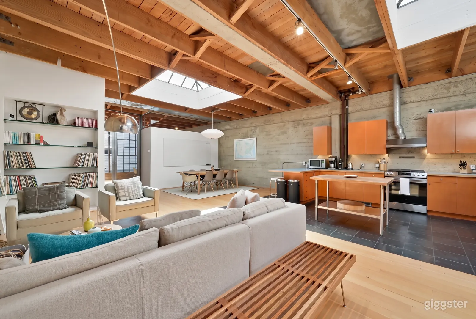 A seminar room has a ceiling with wood beams, warm wood accent shelving, and beige seating of various forms.