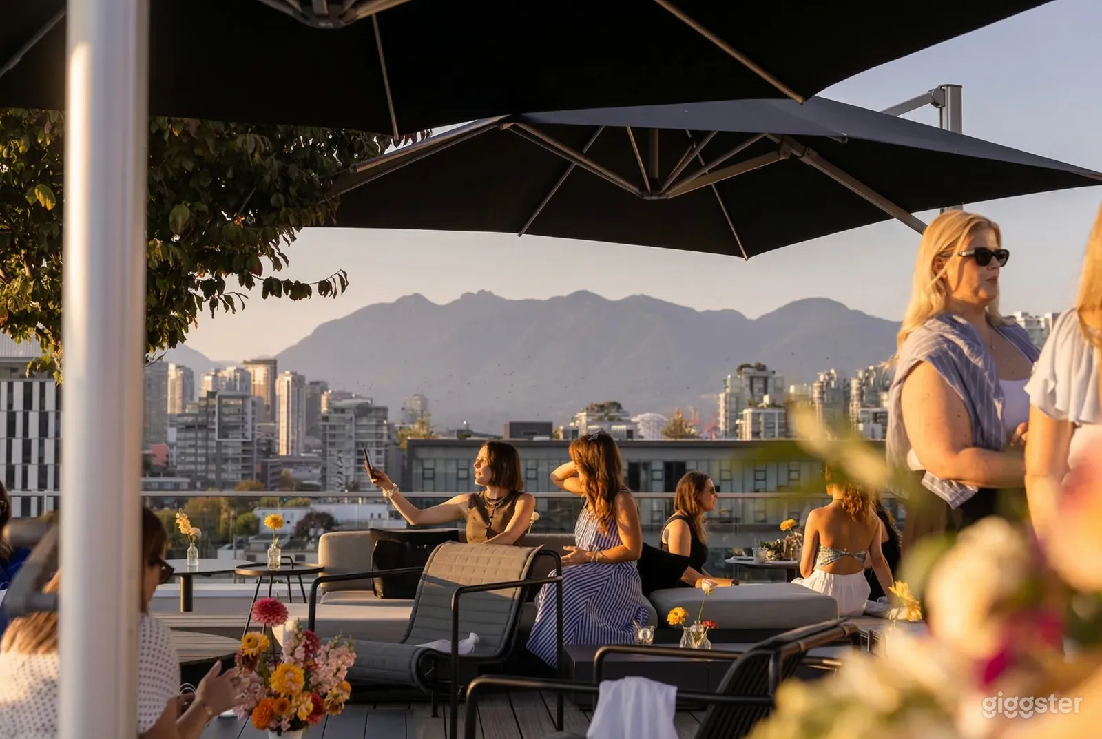 Women are seated in multiple spots on a rooftop venue with mountain views in the background.