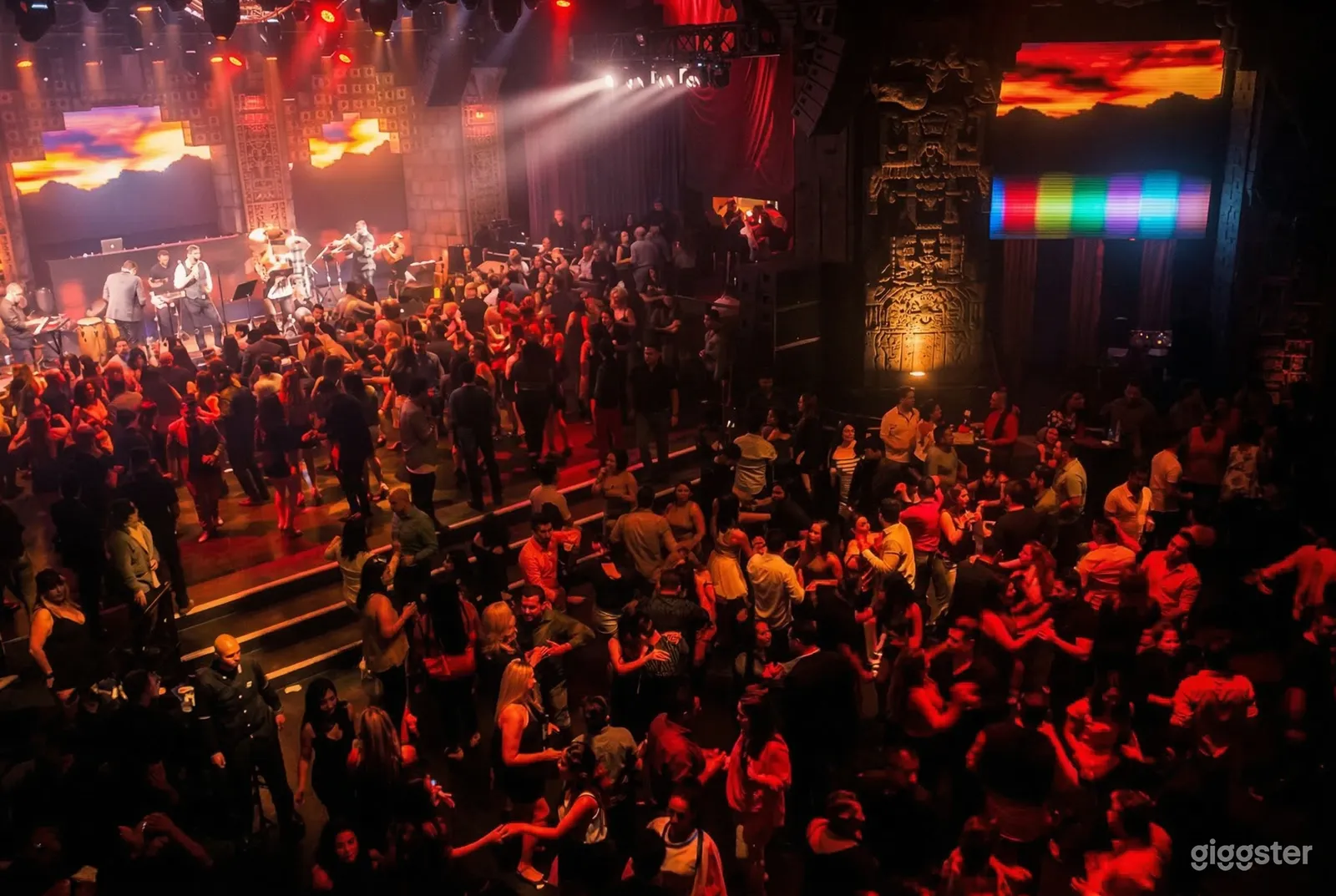 A club's dance floor is filled with people dancing in front of a live band.