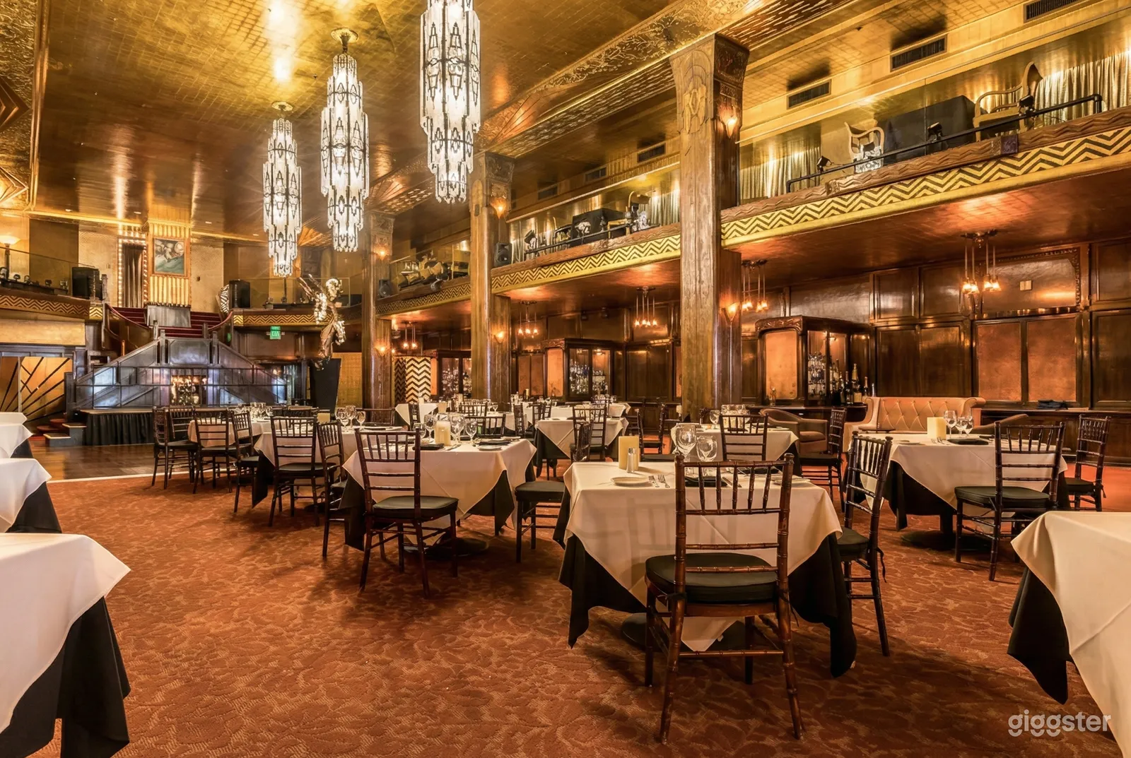 Large restaurant-type venue with two levels and many tables set with white tablecloths, cutlery and wine glasses.