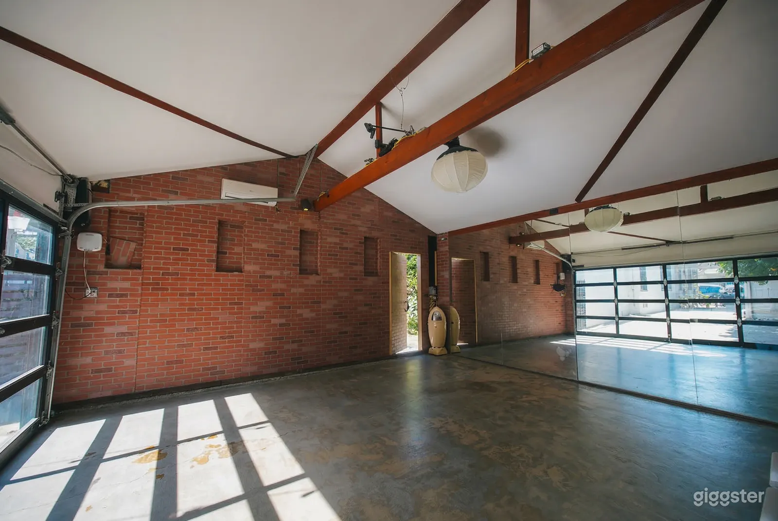 A garage space with brick walls has bright glass doored entrances on either side.