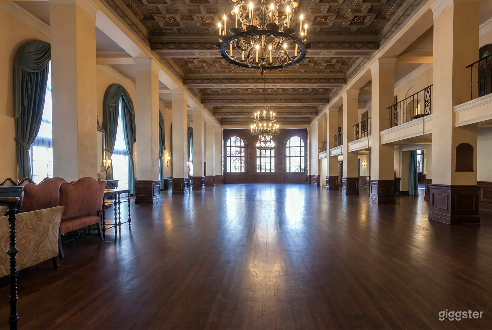 A ballroom with columns on either side and arched windows at the end.