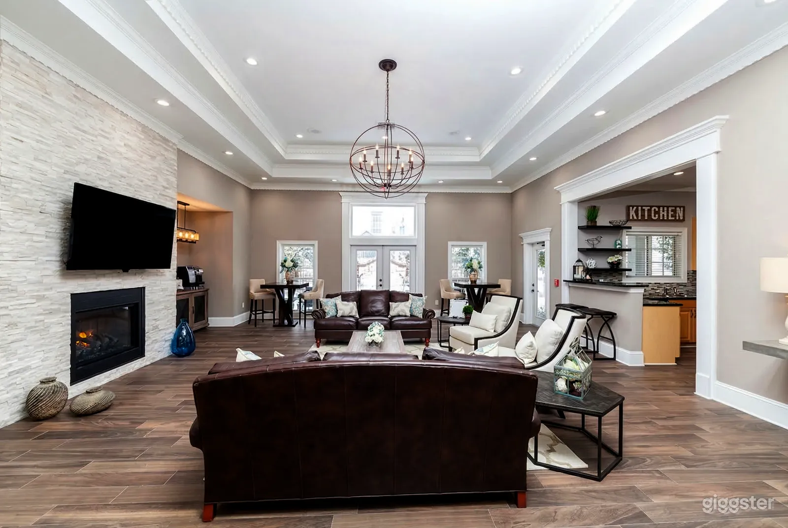 A home's large focal room with brown leather couches, white fireplace and layered ceiling adorned by pot lights.