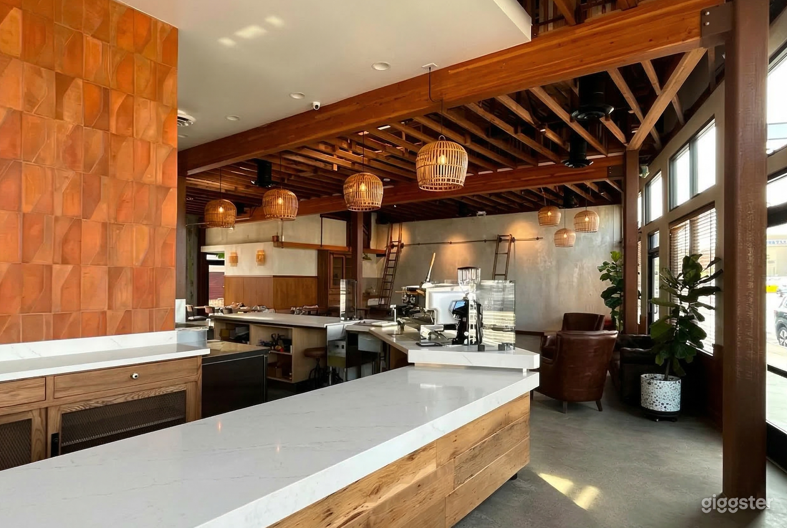 A large angled countertop is central in a room with a wood slat ceiling and hanging wicker covered lighting.