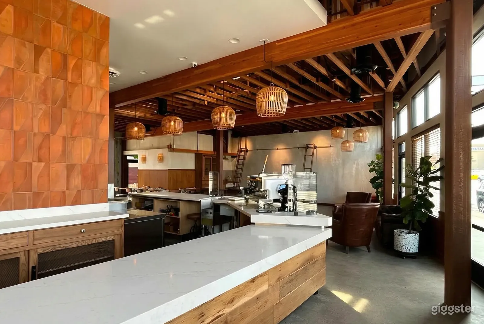 A large angled countertop is central in a room with a wood slat ceiling and hanging wicker covered lighting.