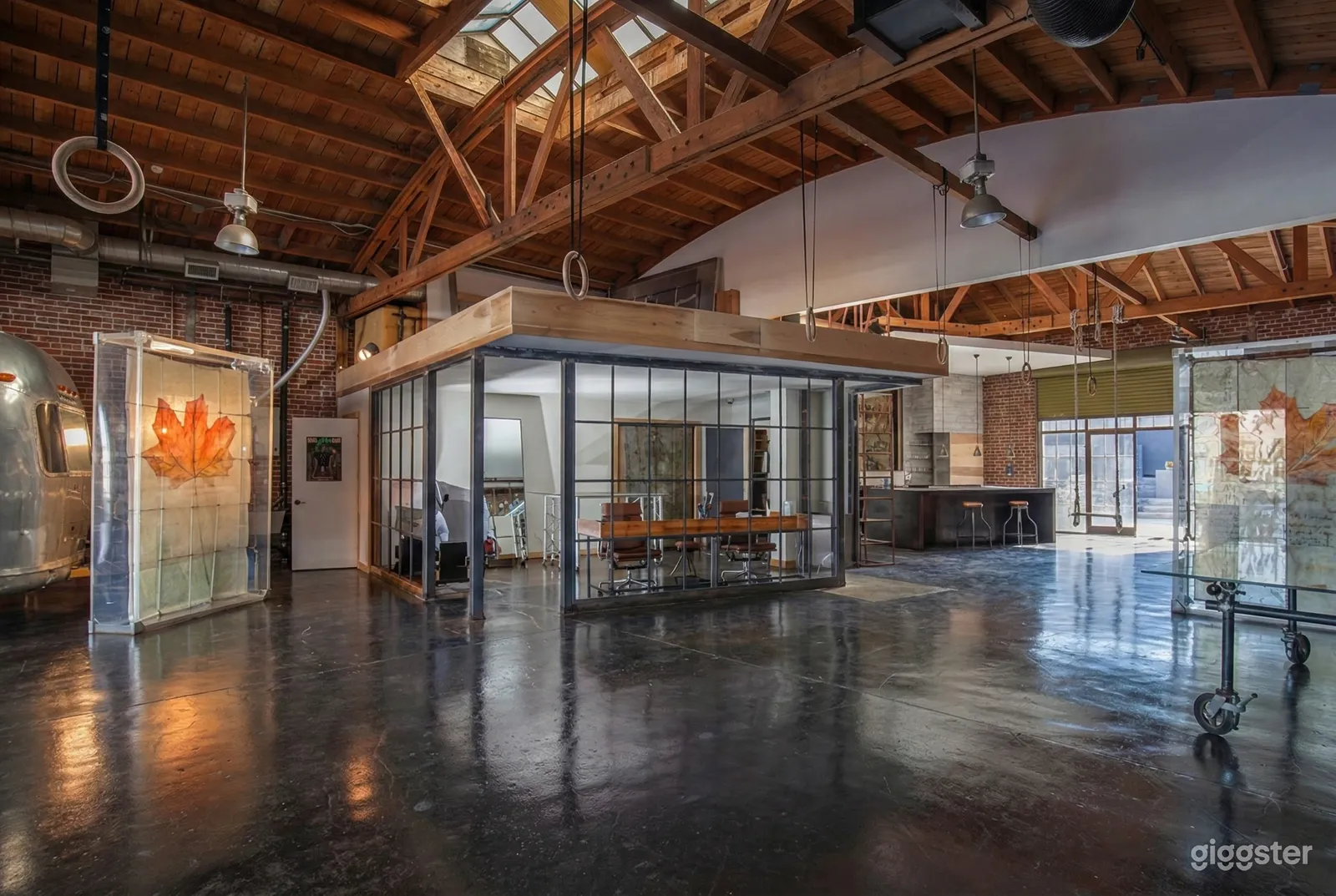 A large modern loft with framed ceilings and a glassed in dining area.