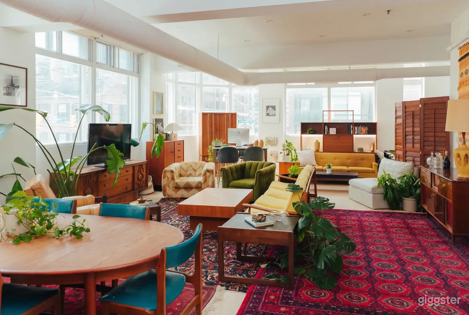 A red patterned carpet covers the floor in a room with seating in varying sizes and colors, along with bureaus of different sizes.