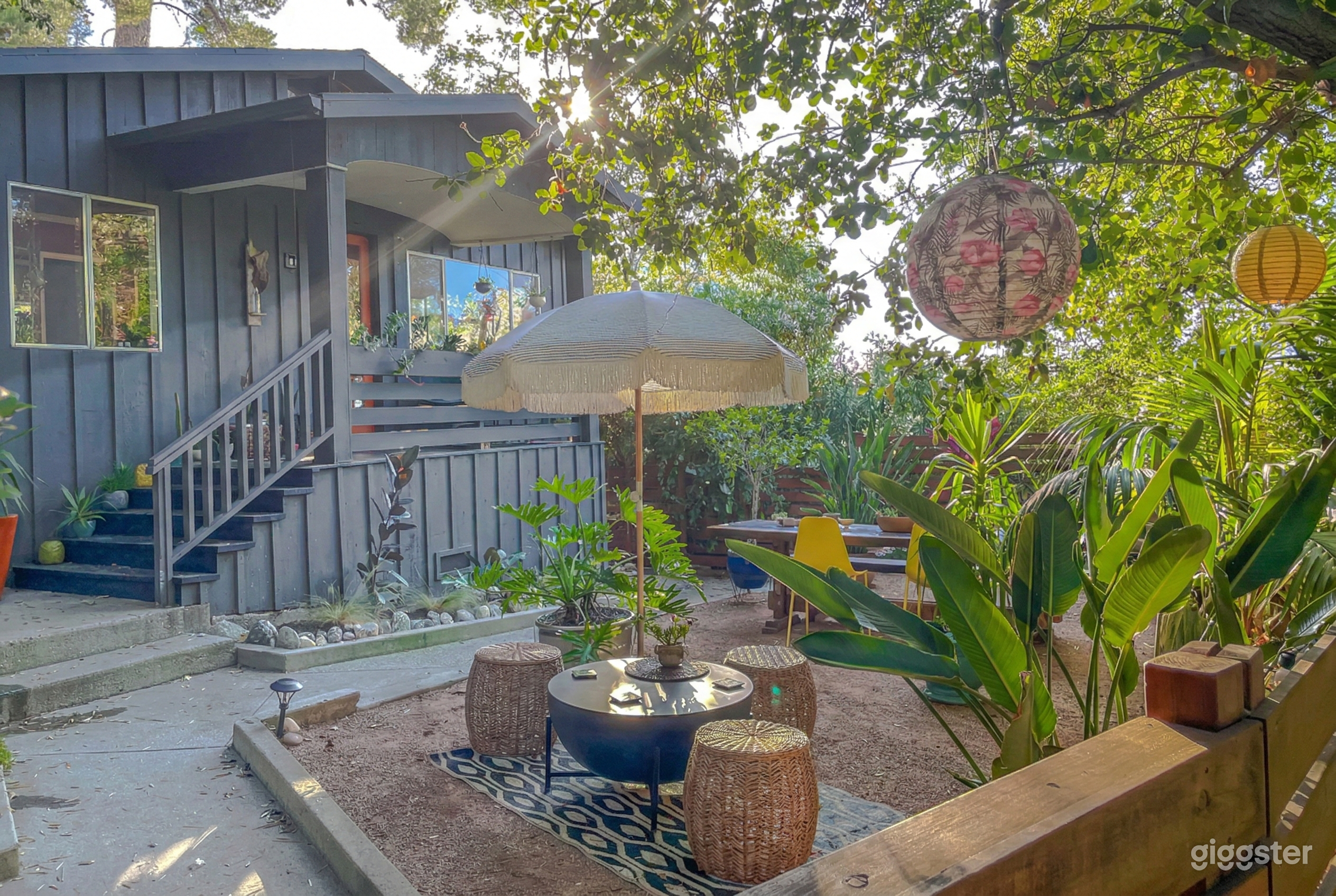 Tables of wicker and wood in a lush green tropical garden setting.