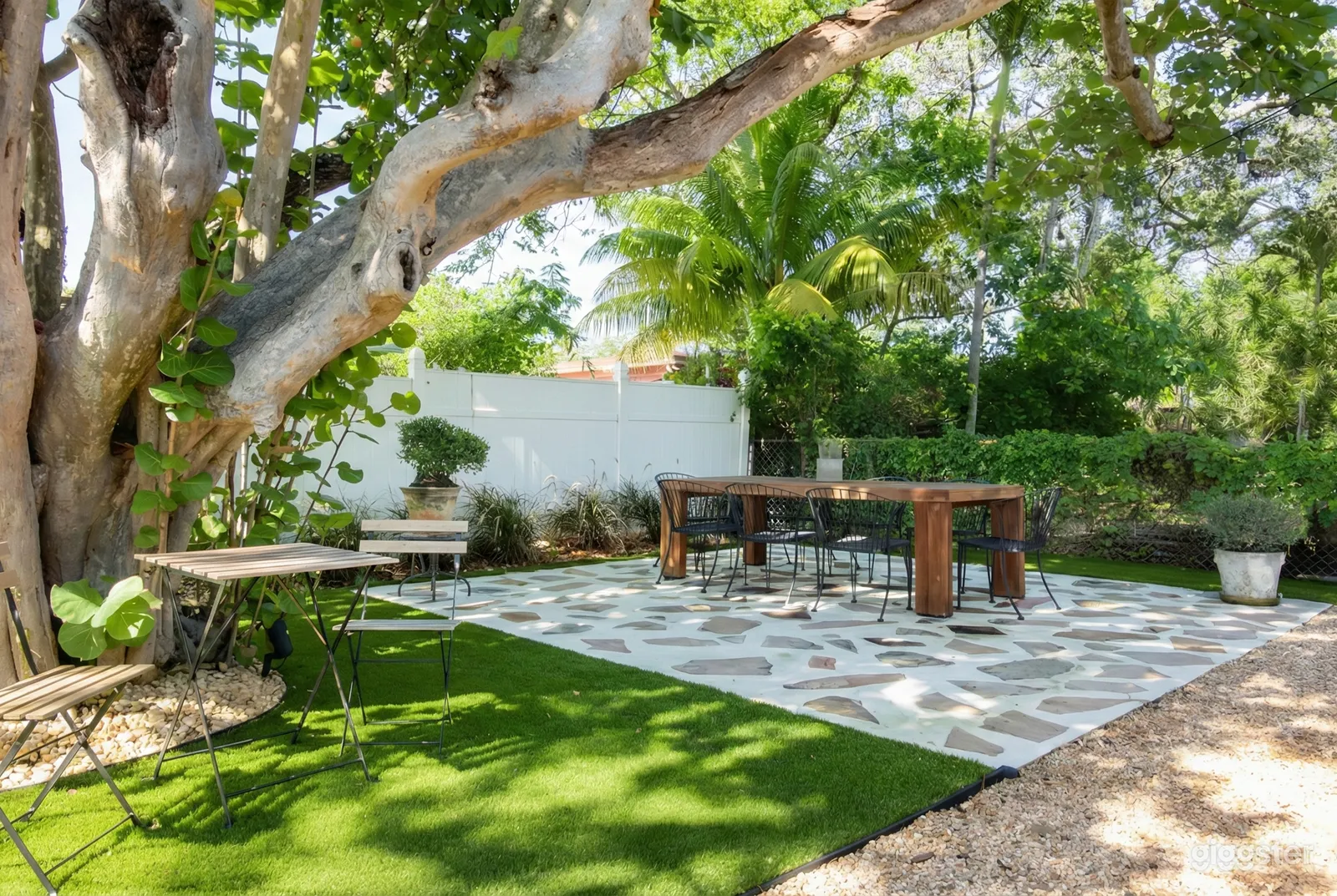 A bridal shower table on a stone patio under trees as prep for a bridal shower.