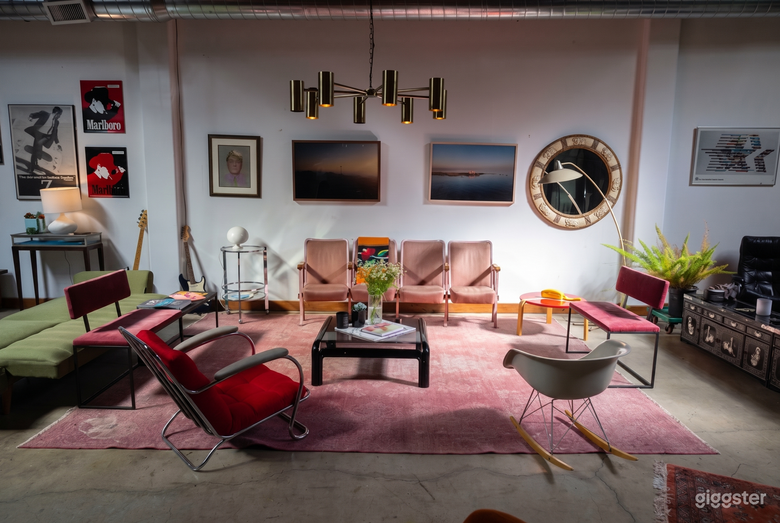 A room with various types of seating on a pink carpet covering a cement floor, with different sizes and styles of art on the wall.