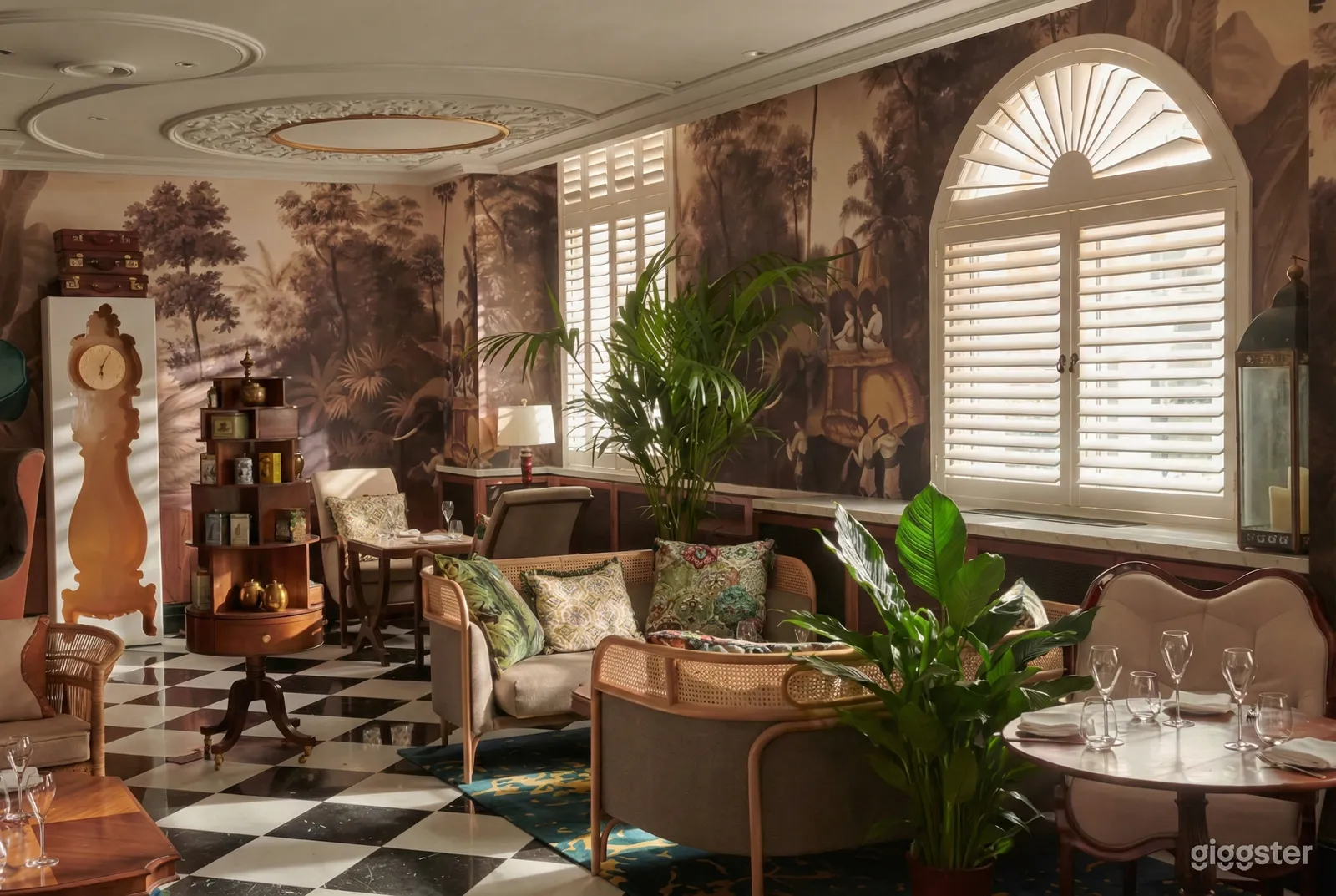 Comfortable seating is the focus of a garden style room with large plants, a checkered floor and decorative wall paper.