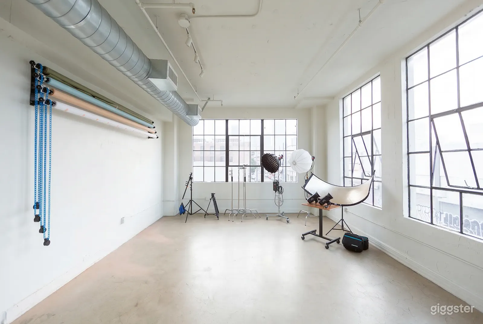 An indoor photo shoot studio is equipped with additional lighting and large paned windows.