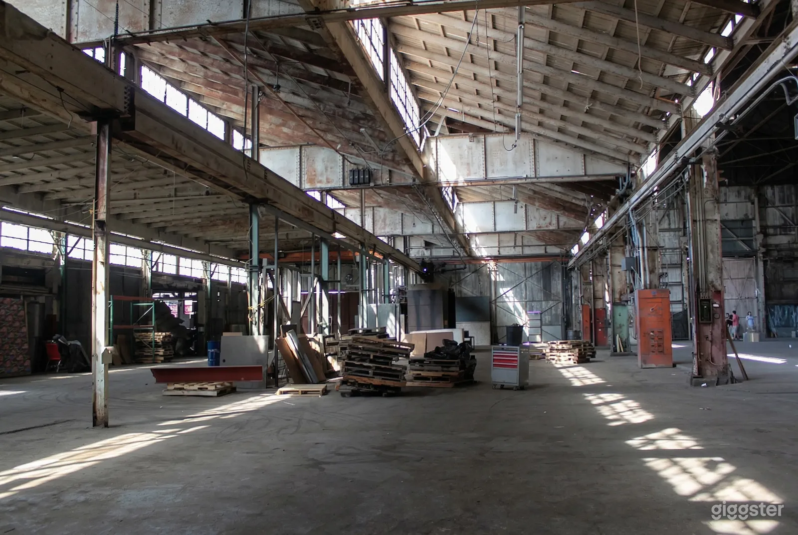 Wood pallets and construction staging sit in a large warehouse studio.