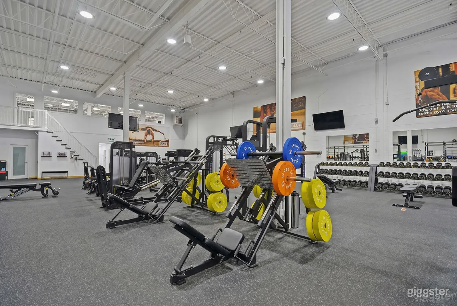 Weightlifting equipment sits in the middle of a well-lit gym space.