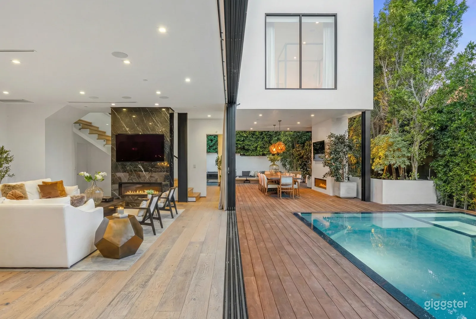 Open concept room with fireplace seating and dining space overlooking a pool.