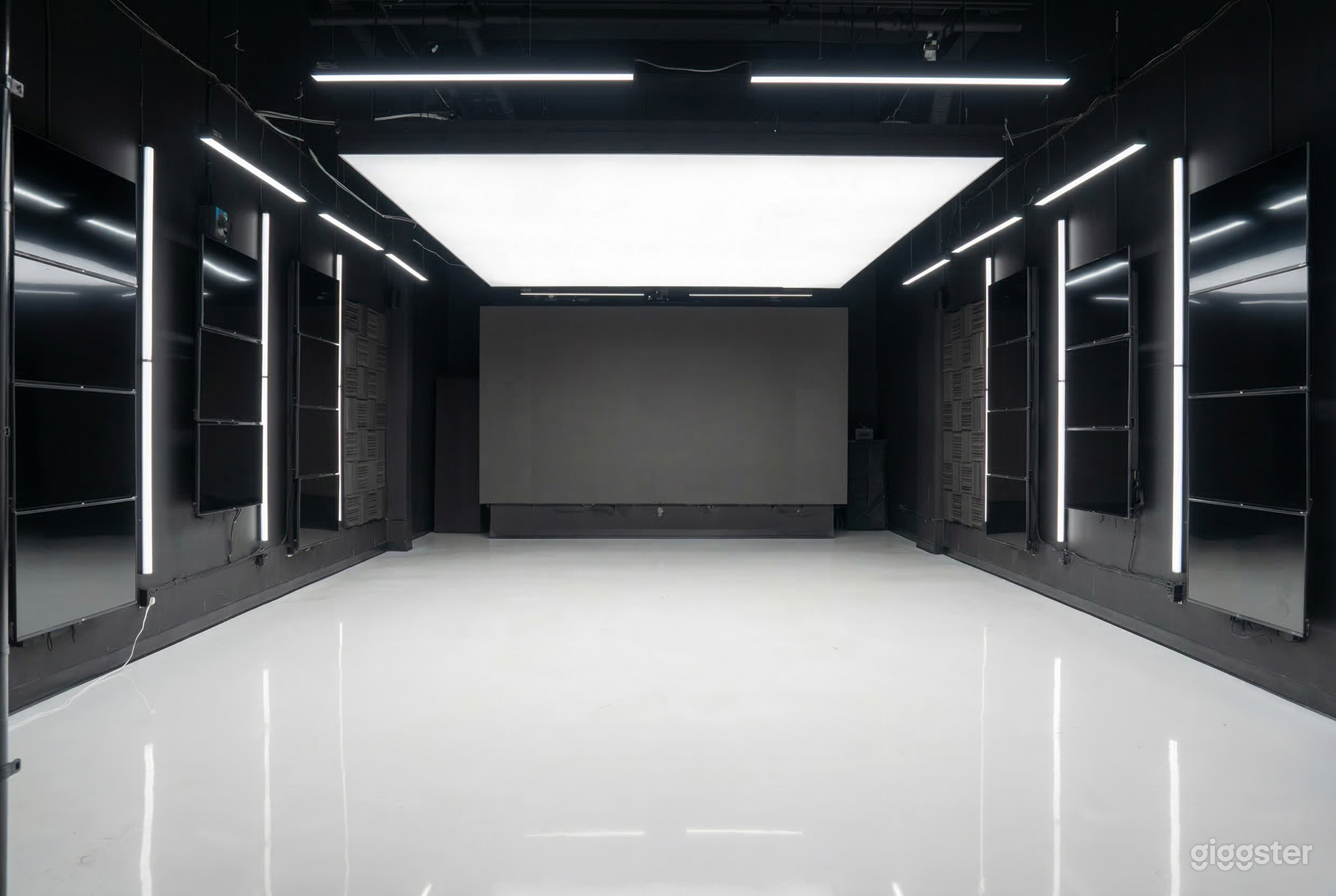 An empty room with shiny white ceramic floors, black walls and a white ceiling.