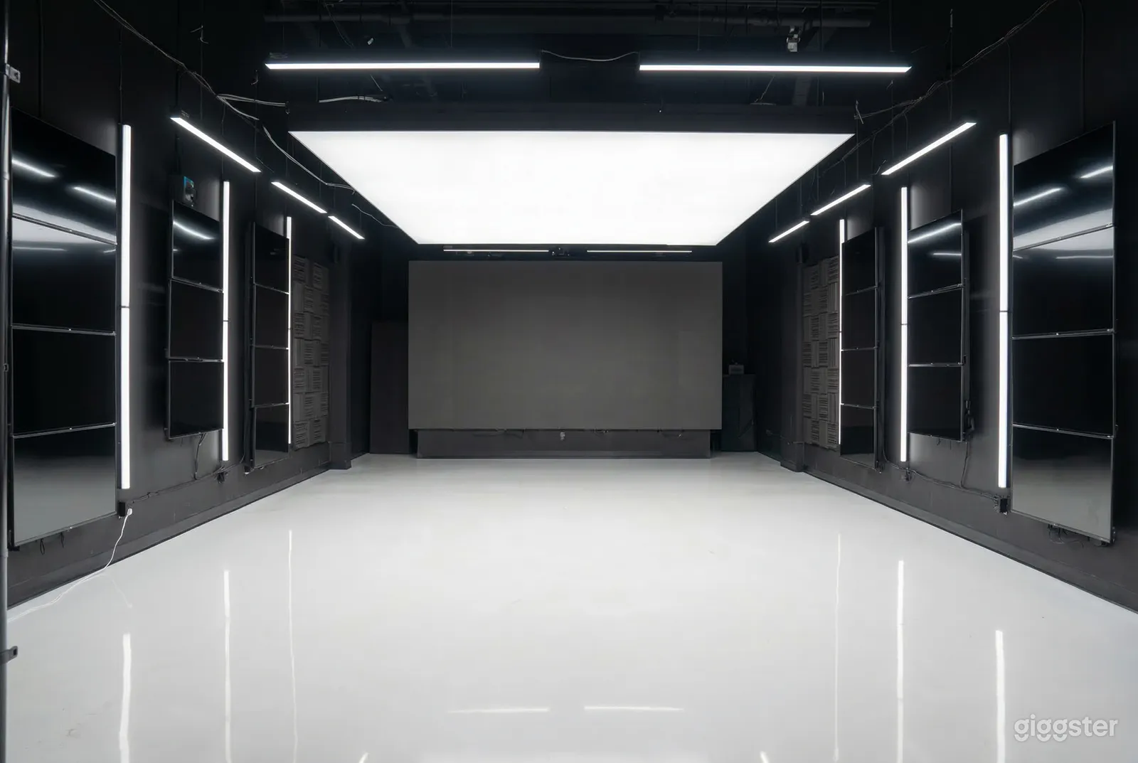 An empty room with shiny white ceramic floors, black walls and a white ceiling.