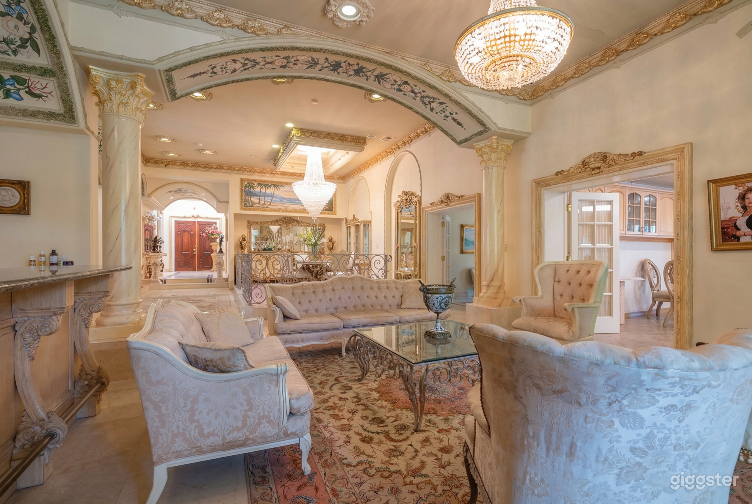 A Spanish style room has intricate detailing on the ceiling and walls, along with old-tradition couches and chairs.