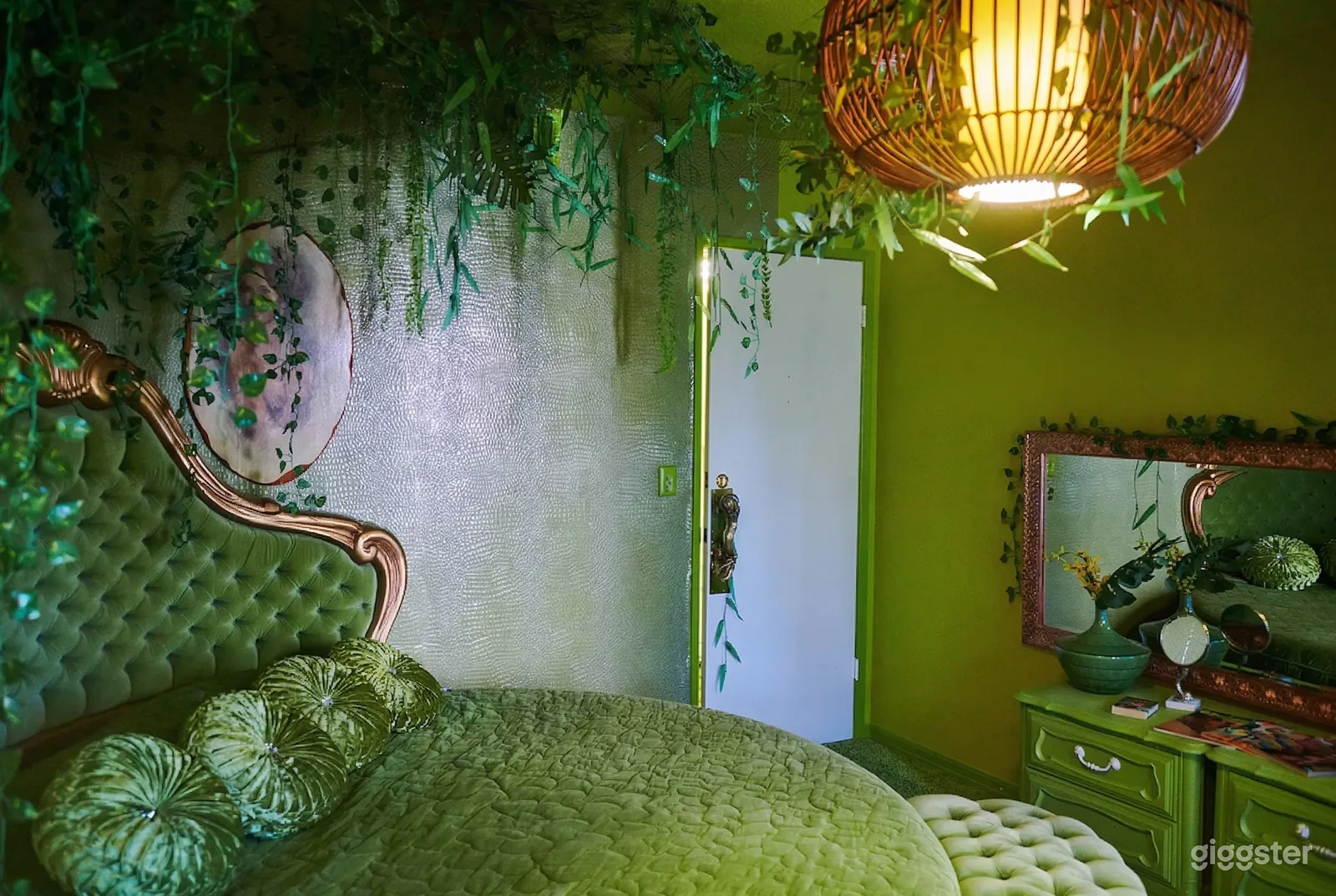 Vines are overhead of an ornate headboard and bed, all are green as are the walls.