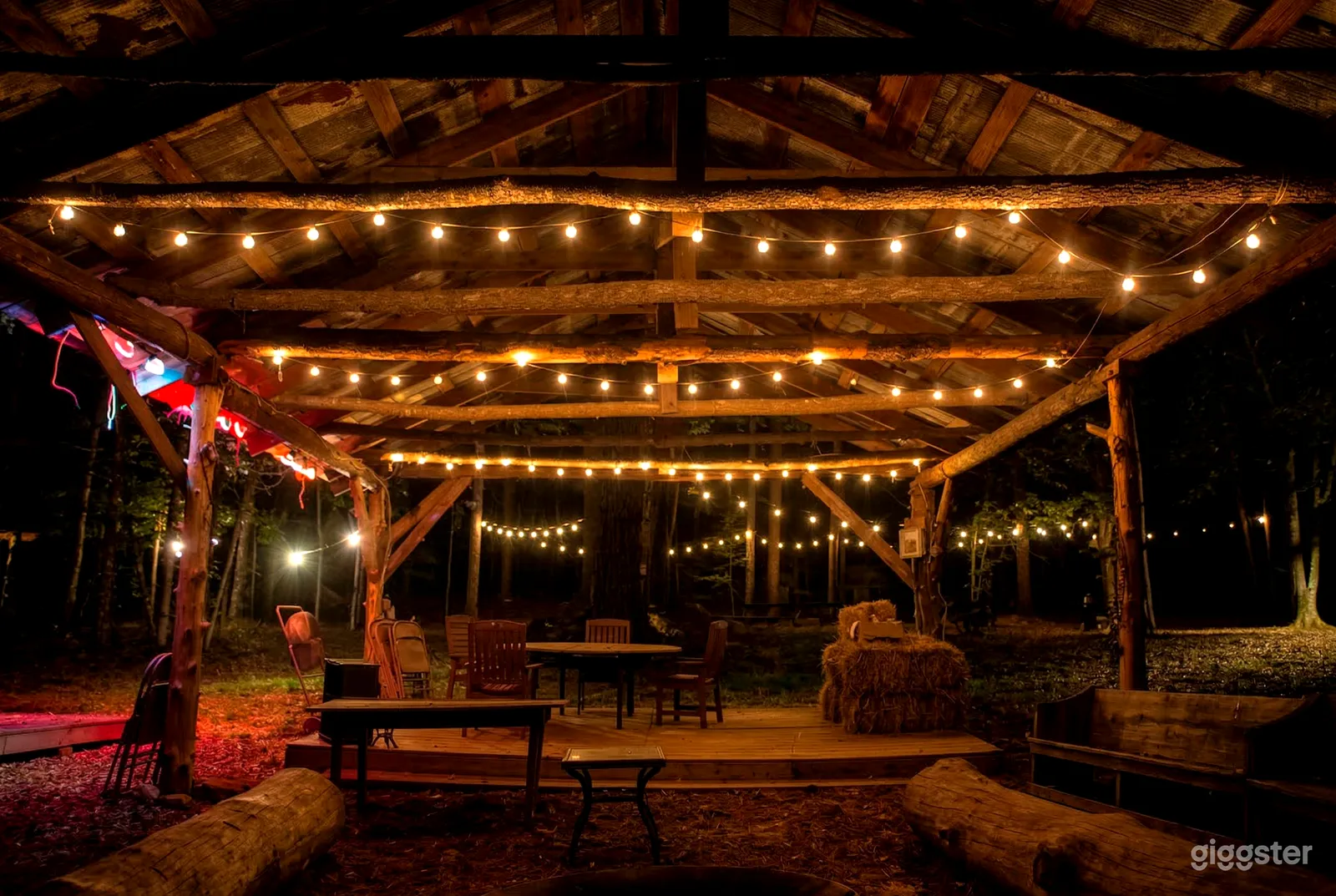 A farm style covered dance floor is decorated in string lights . 