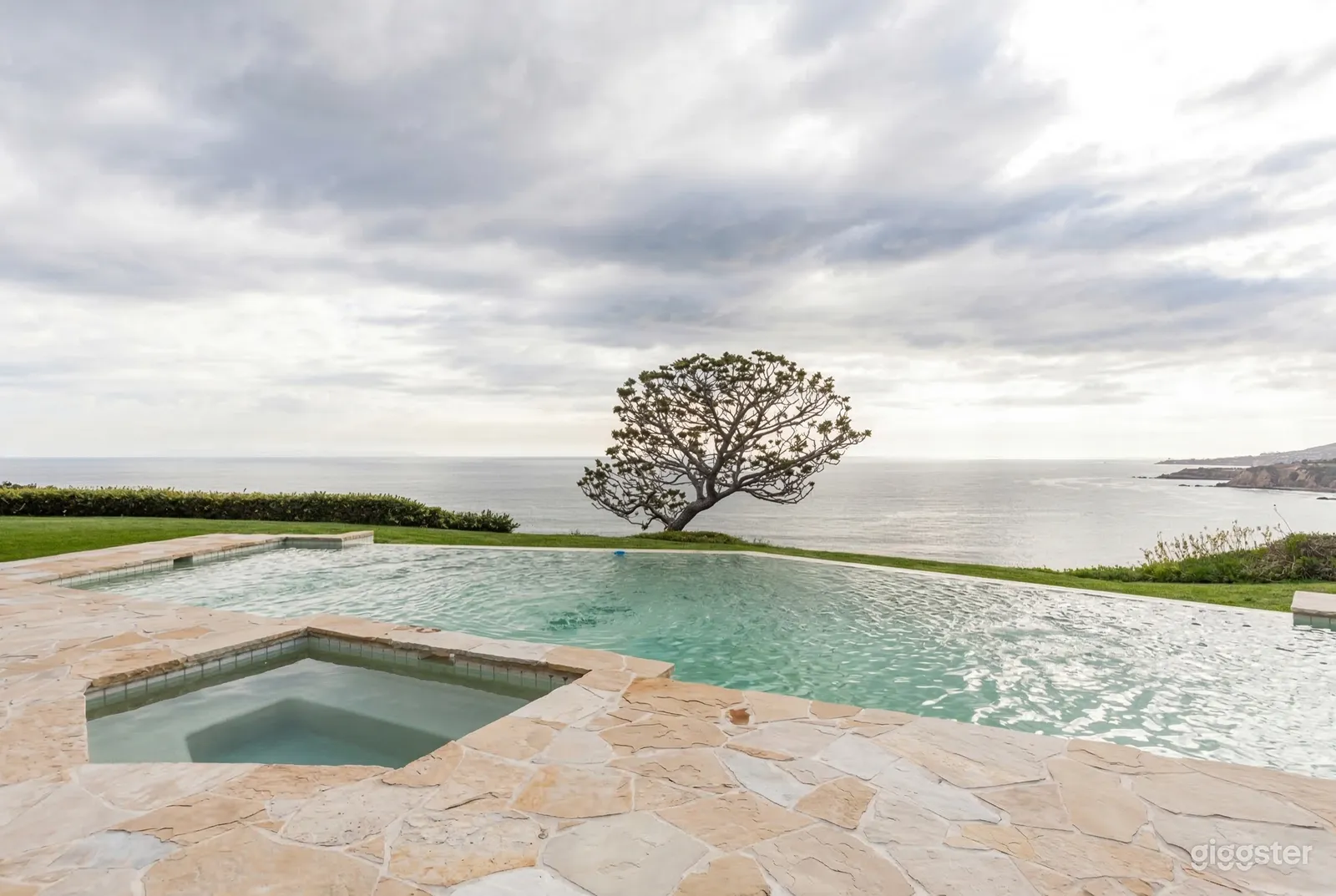 An expansive stone patio leads to a huge infinity pool overlooking the water.